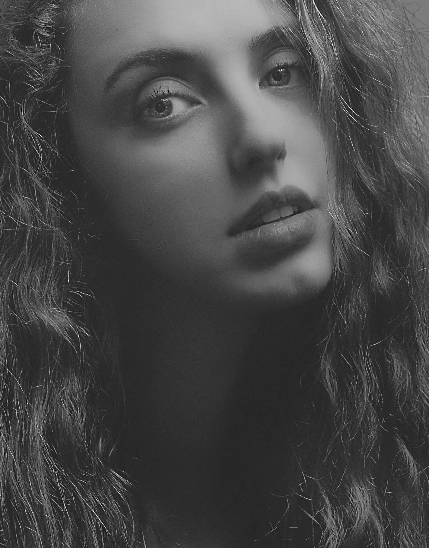 Artistic black and white portrait of a woman with curly hair.